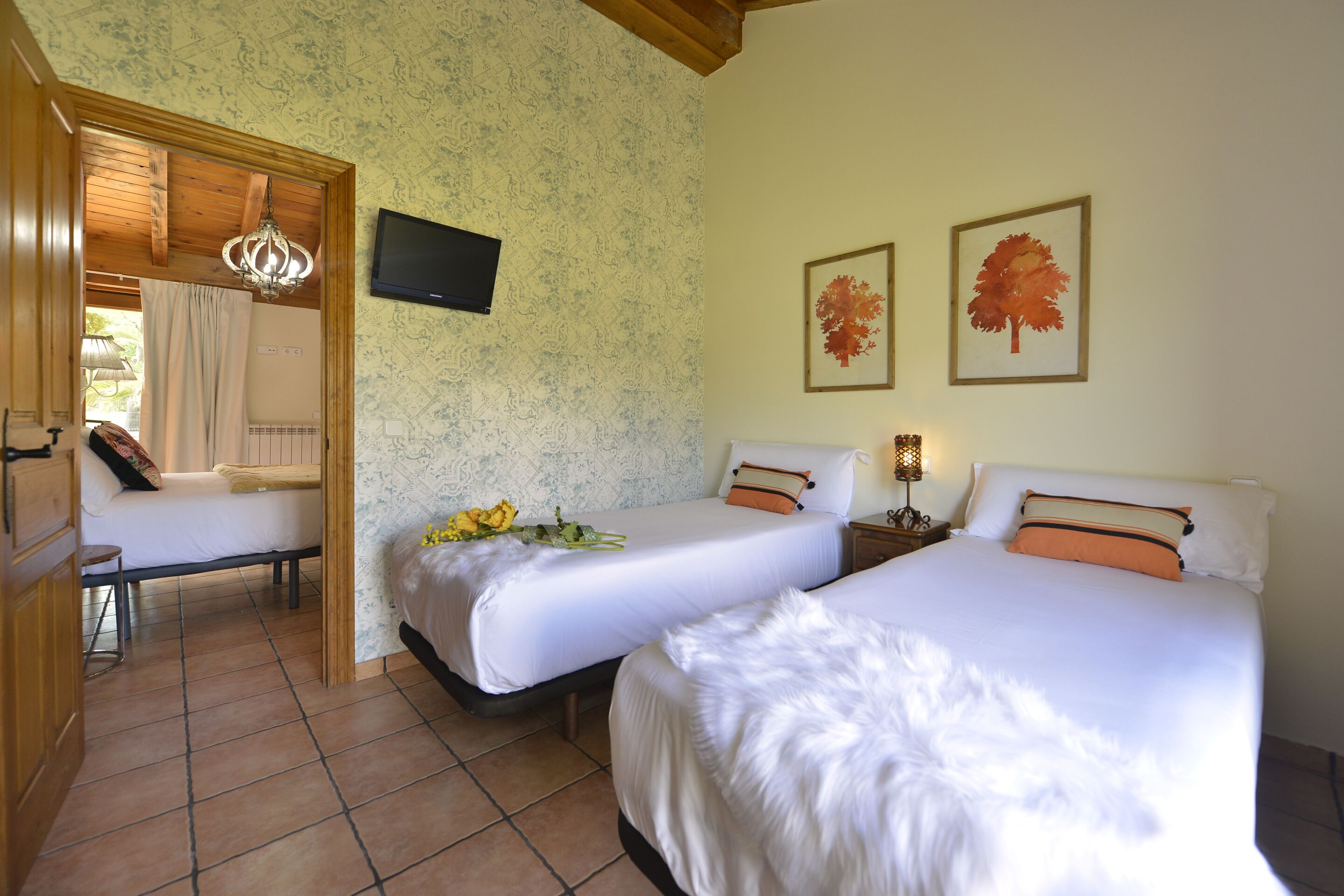 Una habitación de hotel con dos camas, televisión y un candelabro.