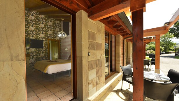A room with a bed, a stone wall, and a wooden ceiling. - El Puentuco (Villacarriedo)