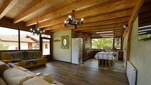 A spacious living area with a wooden ceiling, a dining table, and a kitchen in the background. - El Puentuco (Villacarriedo)