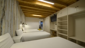 A hotel room with two beds, a TV, and a wooden ceiling. - El Puentuco (Villacarriedo)