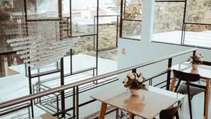 A modern interior with large windows, a glass art installation, and a dining area with tables and chairs. - Antope - Apartaestudios (Cali)