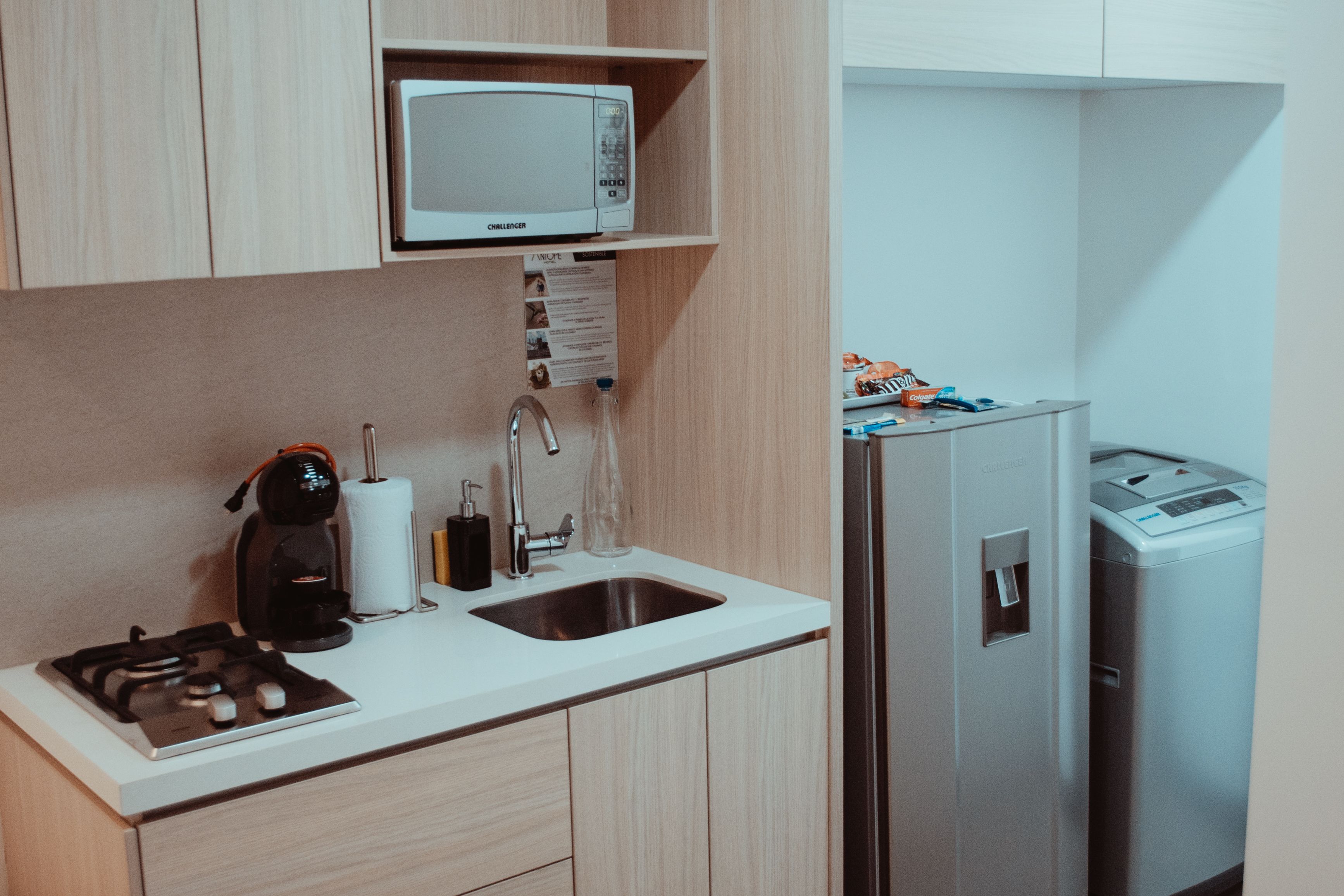 A compact kitchenette with a microwave, coffee maker, sink, and a small refrigerator.