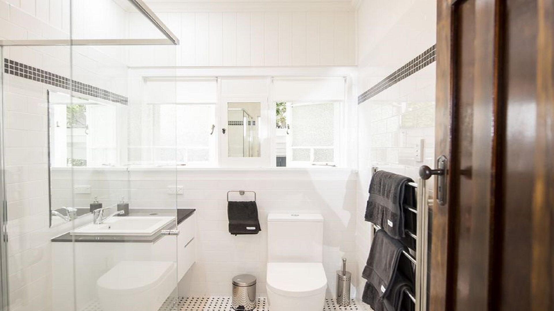 A modern bathroom with a glass shower enclosure, a sink, and a toilet.