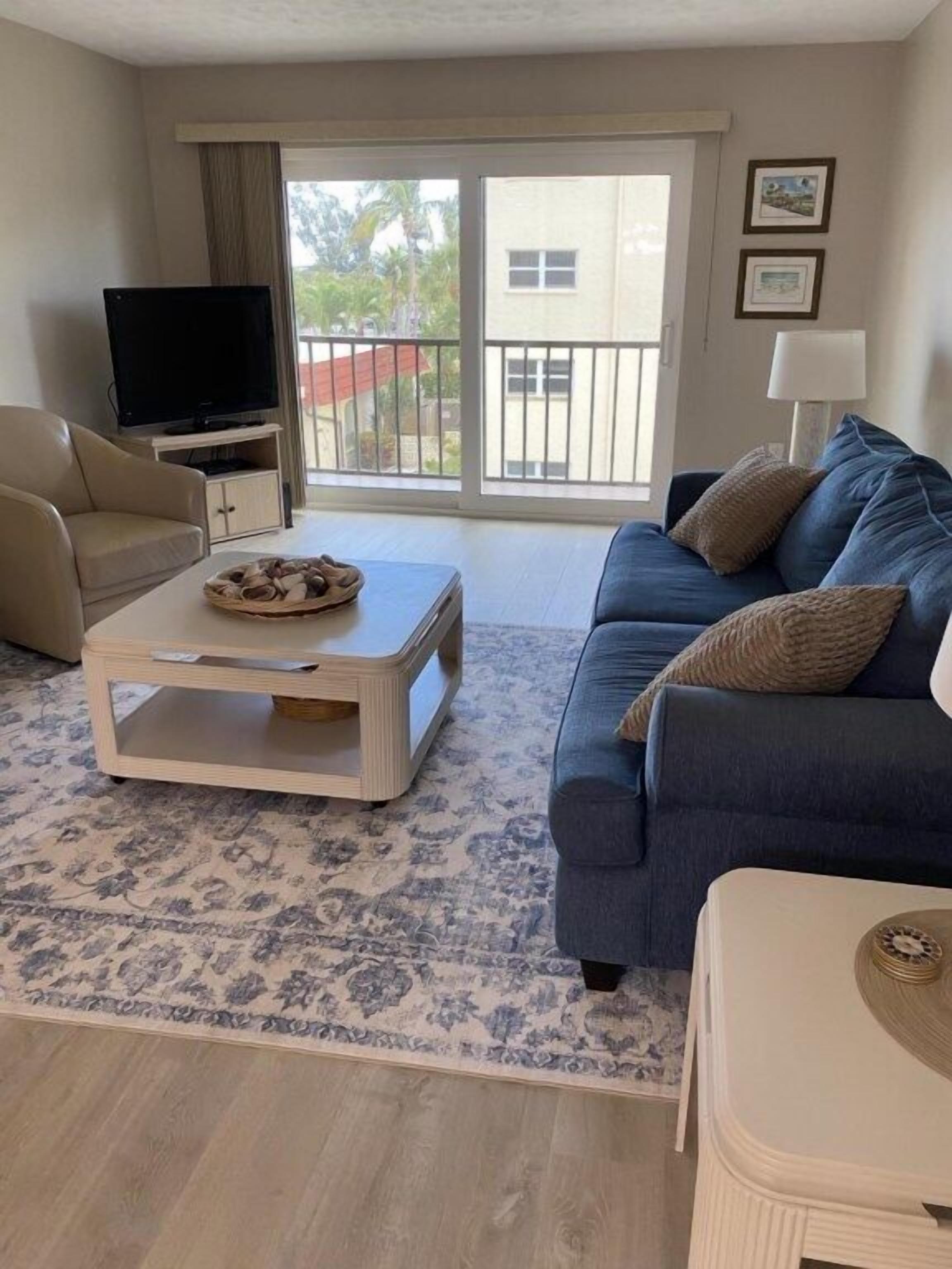 Een woonkamer met een bank, salontafel, televisie en een balkon met uitzicht.