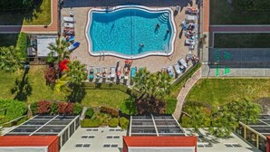 An aerial view of a swimming pool surrounded by lounge chairs and umbrellas, with a clear sky above. - Condo# 314 Siesta Key 3rd Flr 2b/2b unit; Open kitchen; newly renovated master shower (Sarasota)