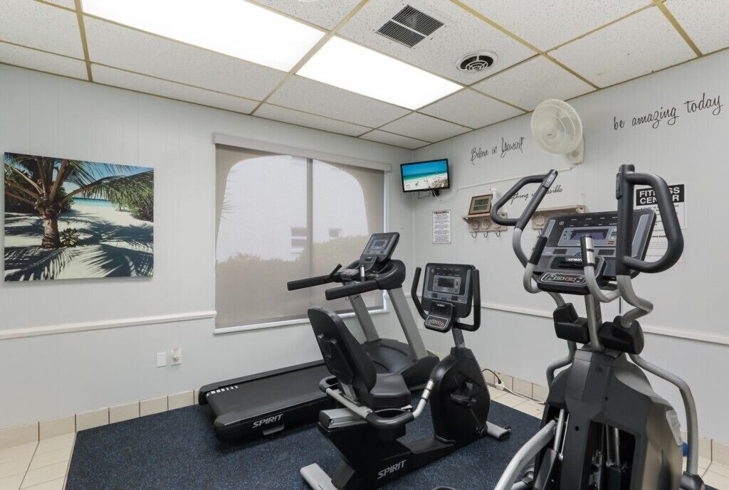 Une salle de sport équipée de deux appareils de cardio, d’un tapis de course et d’un vélo d’appartement.