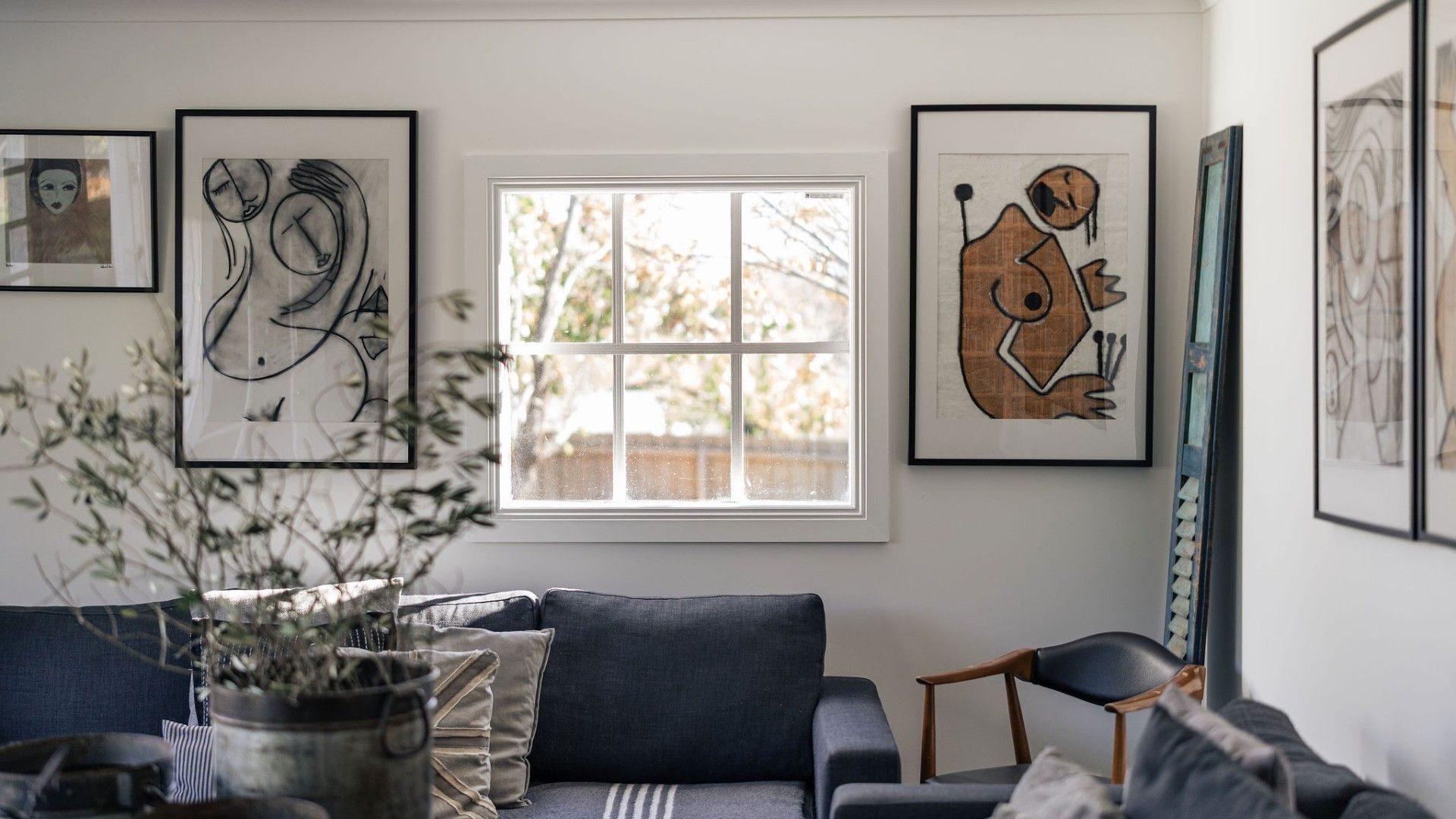 Ein Wohnzimmer mit einer Couch, einem Fenster und abstrakter Kunst an den Wänden.