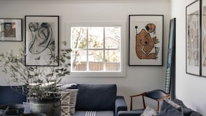 A living room with a sofa, a window, and abstract art on the walls.
