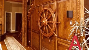 Eine Holztür mit Schiffslaufrad-Design, eine Treppe und ein Blumentopf.