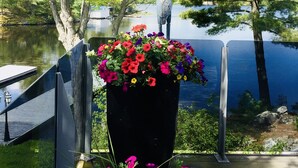 Ein Weg, der zu einem See führt, mit einem großen Pflanzgefäß voller bunter Blumen und einer Statue.