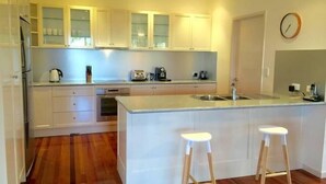 A modern kitchen with white cabinetry, a central island with stools, and a clock on the wall.