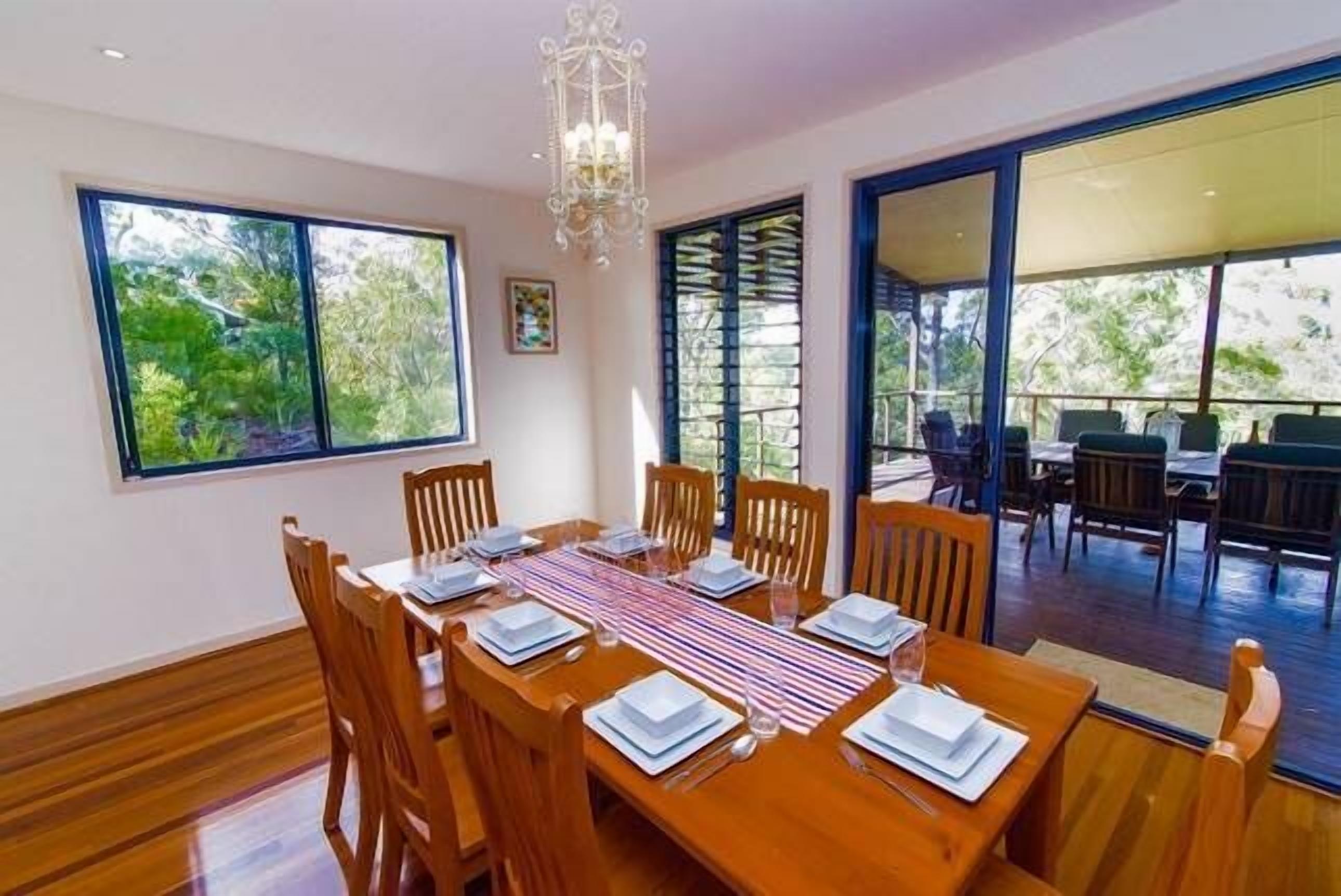A dining area with a wooden table set for six, surrounded by chairs.
