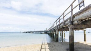 A wooden pier extending into calm waters with a clear sky above.
