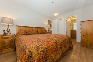 Een slaapkamer met een groot bed, houten nachtkastjes, een lamp en een kledingkast.