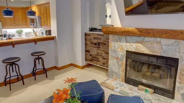 Een moderne keuken met houten kasten, een stenen open haard en een bar met barkrukken.