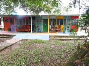 Un bâtiment aux couleurs vives, doté d’un porche, d’un canapé et d’une table.