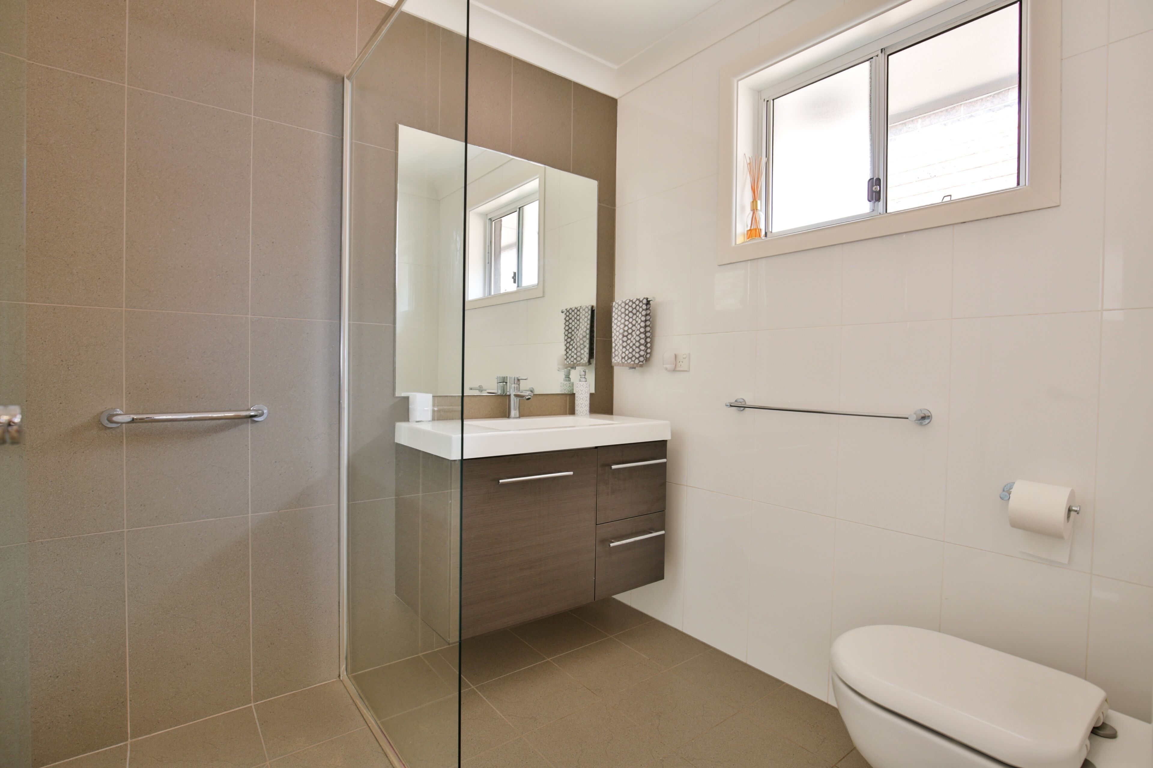 A modern bathroom with a glass shower enclosure, a white toilet, and a vanity with a mirror.