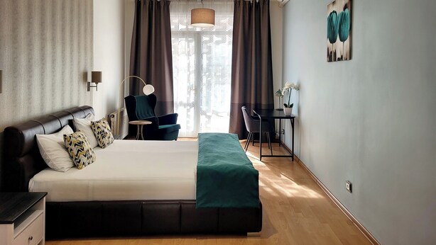 Ein modernes Hotelzimmer mit einem großen Bett, einem Schreibtisch, einem Sessel und einer Pendelleuchte.