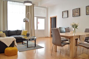 A modern living room with a sofa, coffee table, and dining table with chairs.