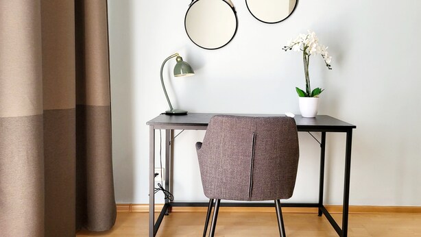 A desk with two round mirrors, a lamp, and a potted plant.
