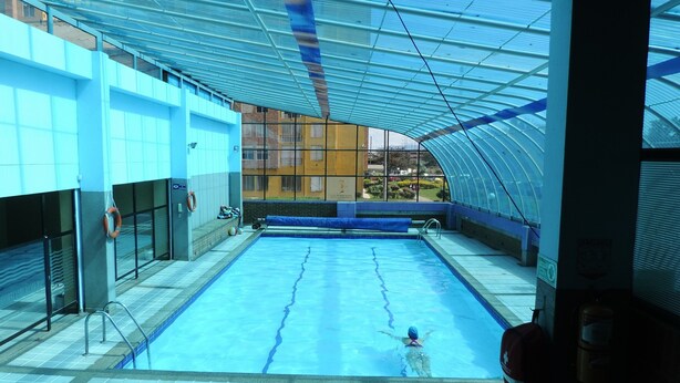 An indoor swimming pool with a clear view of the surrounding buildings. - Apartamento confortable (Bogotá)