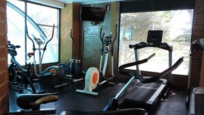 A gym with various exercise equipment including treadmills, stationary bikes, and elliptical machines. - Apartamento confortable (Bogotá)