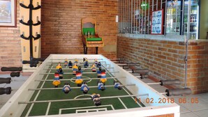 A foosball table in a room with brick walls and a metal gate. - Apartamento confortable (Bogotá)