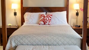 A four-poster bed with a quilted bedspread and a matching bench, two bedside lamps, and a nightstand with a lamp. - Romantic Beachfront Getaway (Maalaea Bay)