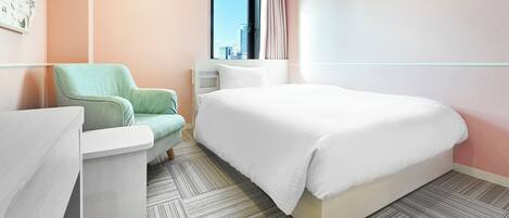 A modern hotel room with a large bed, a seating area with a chair, a small table, and a window with a view of the city.