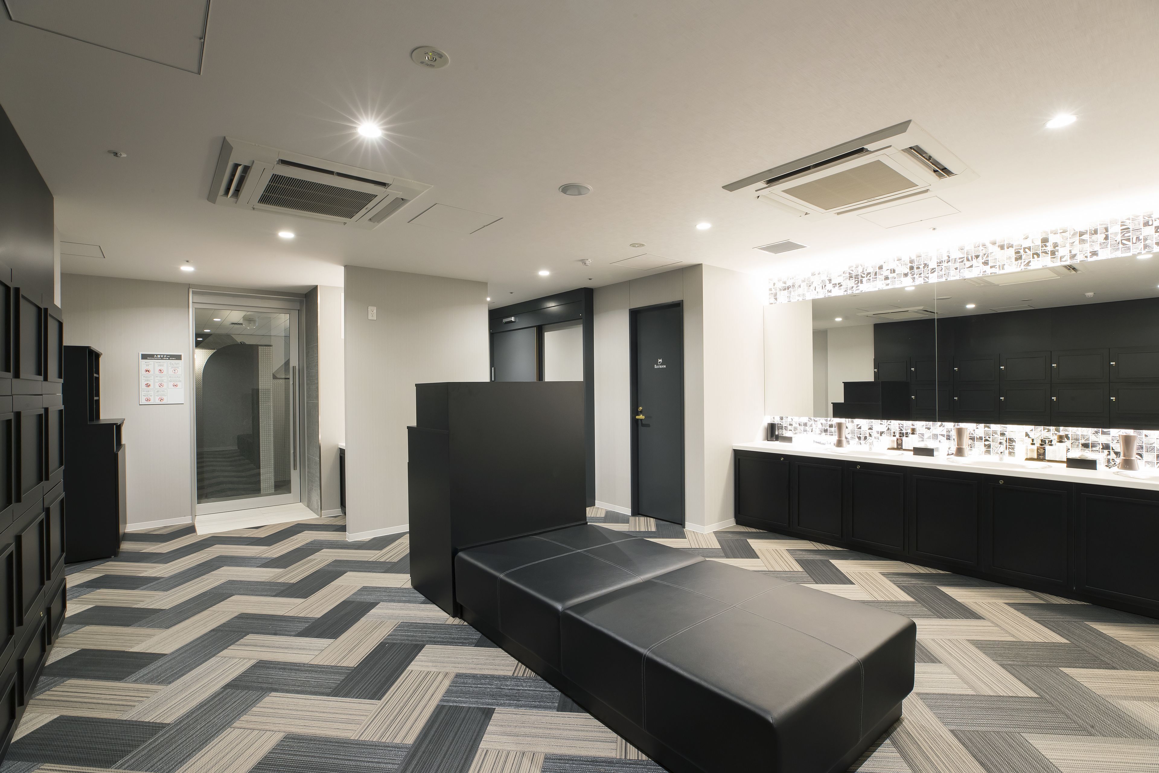 A modern hotel lobby with a black reception desk, a seating area, and a counter with a display.