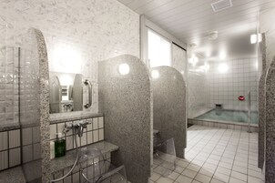 Un bagno moderno con box doccia in vetro, lavandino con specchio e pavimento piastrellato.