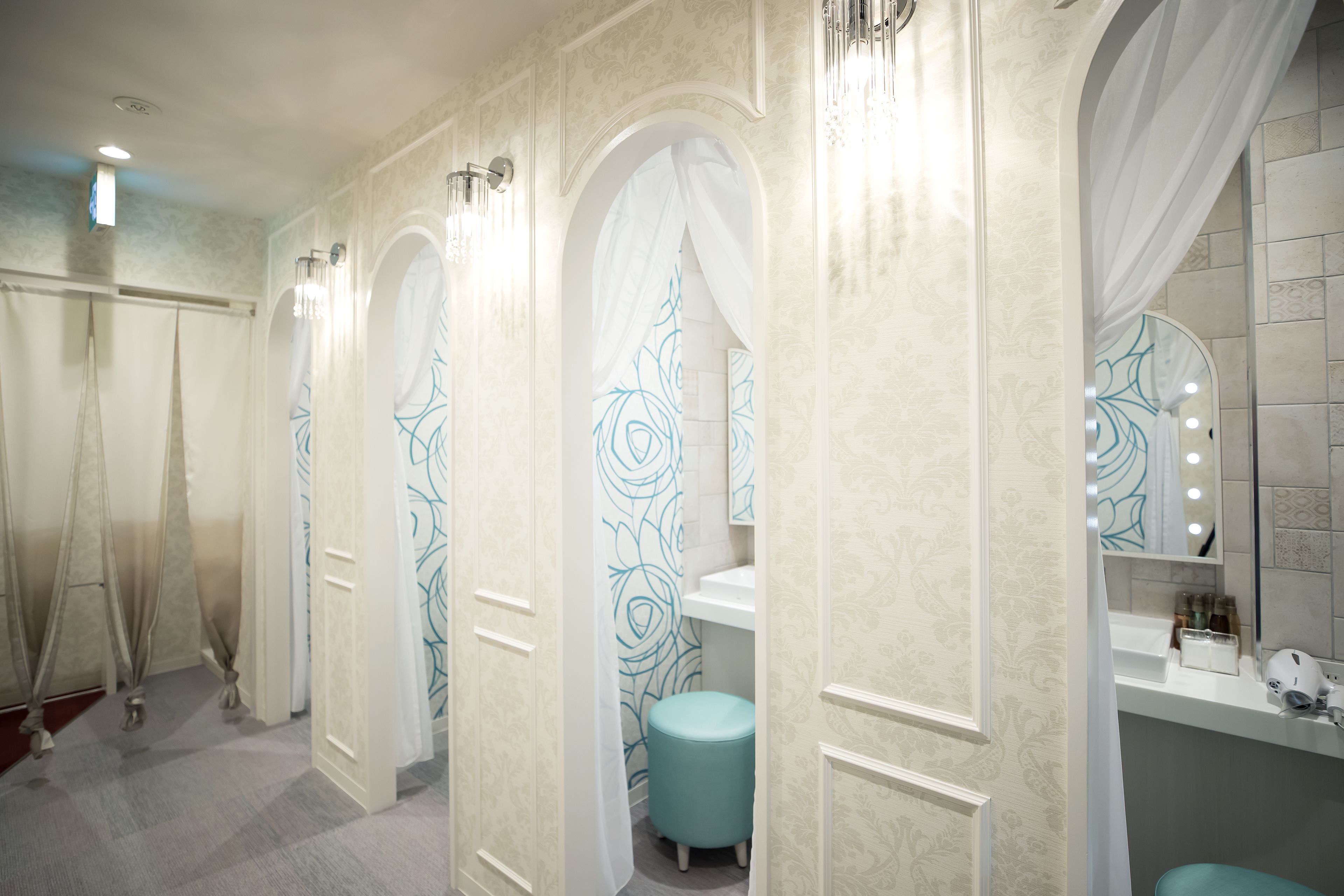 A bathroom with a vanity, mirror, and a round stool.