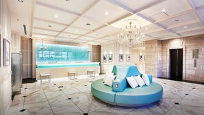 A hotel lobby with a reception desk, a blue seating area, and a chandelier. - DEL style NAGOYA-NAYABASHI by Daiwa Roynet Hotel (Nagoya)