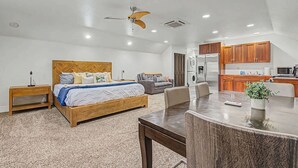 A bedroom with a bed, bedside tables, a ceiling fan, and a kitchenette with a refrigerator and microwave. - Cozy Studio • Trail Access • Walk to Payette Lake (McCall)