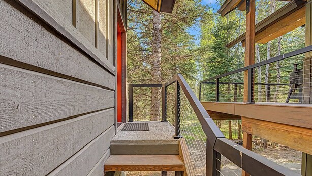 A wooden staircase leading to a deck with a metal railing, surrounded by trees. - Cozy Studio • Trail Access • Walk to Payette Lake (McCall)