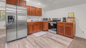 A modern kitchen with wooden cabinets, stainless steel appliances, and a built-in water dispenser. - Cozy Studio • Trail Access • Walk to Payette Lake (McCall)