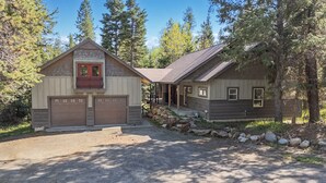 A two-story cabin with a garage, a covered porch, and a stone foundation. - Cozy Studio • Trail Access • Walk to Payette Lake (McCall)