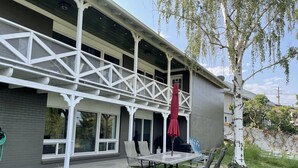 A house with a covered porch, a picnic table, and a red umbrella.