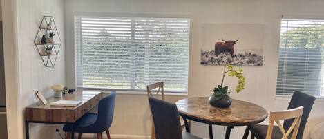 A dining area with a round table, chairs, a desk, and a bookshelf.