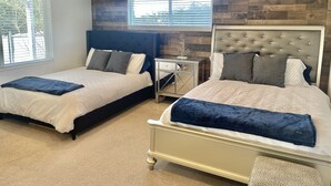 A bedroom with two beds, a nightstand, and a mirror.