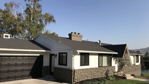 Ein zweistöckiges Haus mit Steinfundament, Garage und einem angelegten Vorgarten.