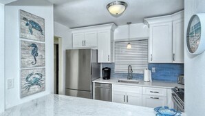 A modern kitchen with white cabinets, stainless steel appliances, and a marble countertop. - Condo# 309 Fully renovated 1b/1b unit with great views of the gulf (Sarasota)