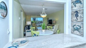 A modern kitchen with a marble countertop, a round dining table with chairs, a hanging light fixture, and artwork on the walls. - Condo# 309 Fully renovated 1b/1b unit with great views of the gulf (Sarasota)