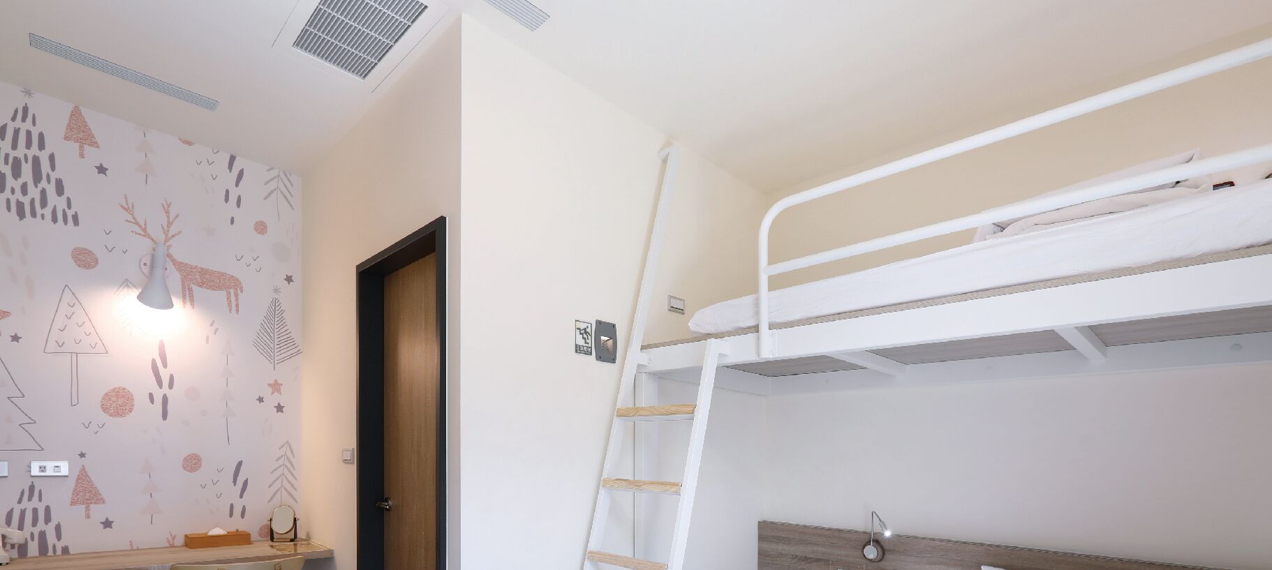 A bunk bed room with a wooden door, a wall with abstract patterns, and a ceiling vent.