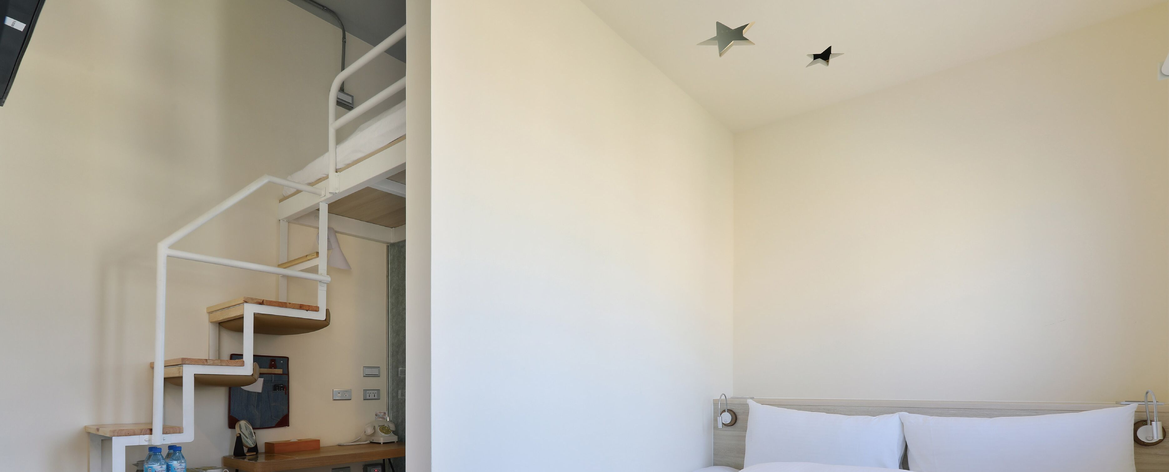 A bedroom with a bunk bed, a desk with a chair, and a nightstand.