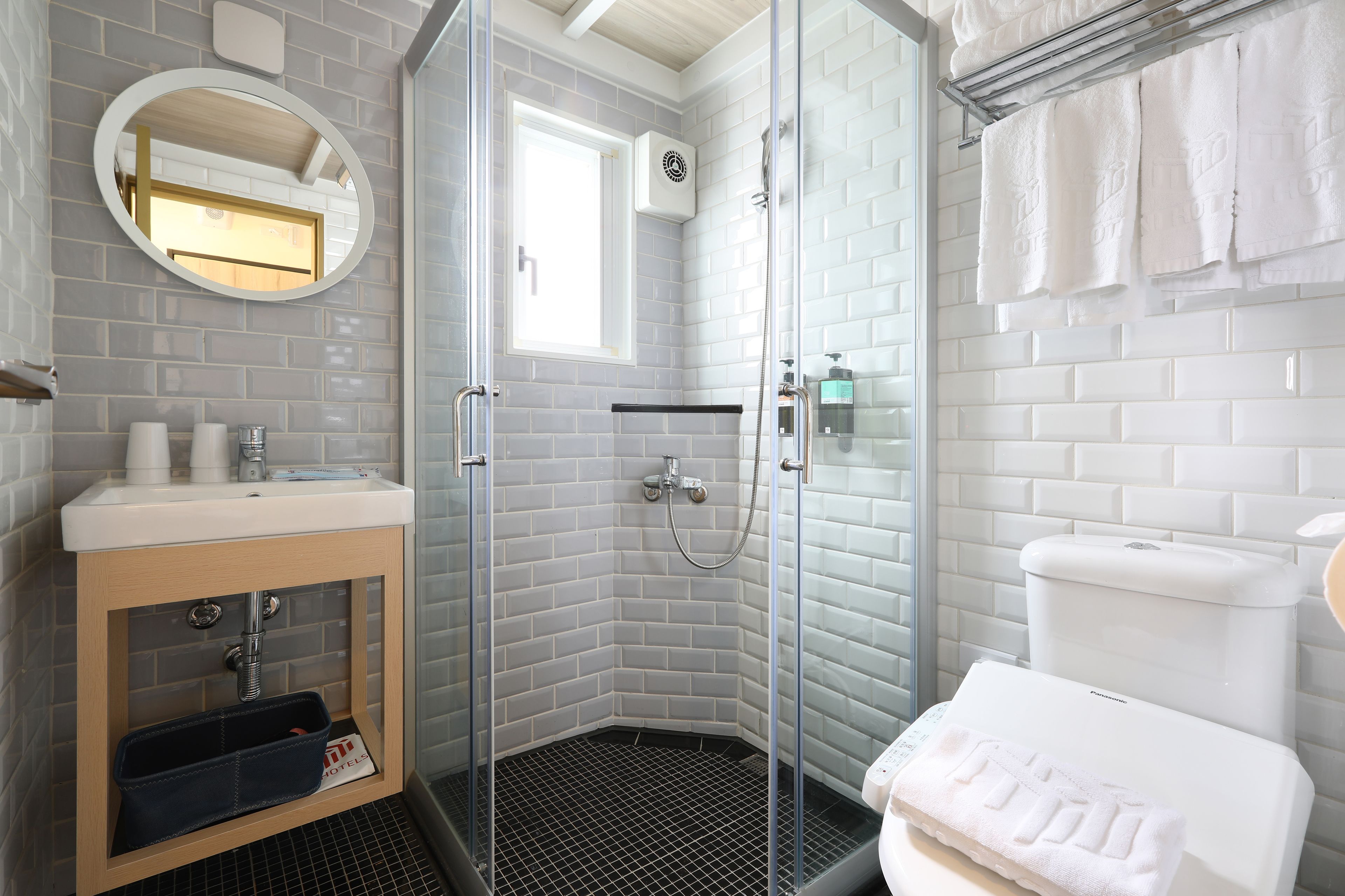 Un baño moderno con cabina de ducha de vidrio, un lavabo con espejo y un inodoro.