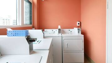 A laundry room with a washing machine, dryer, and a blue basket on a table.