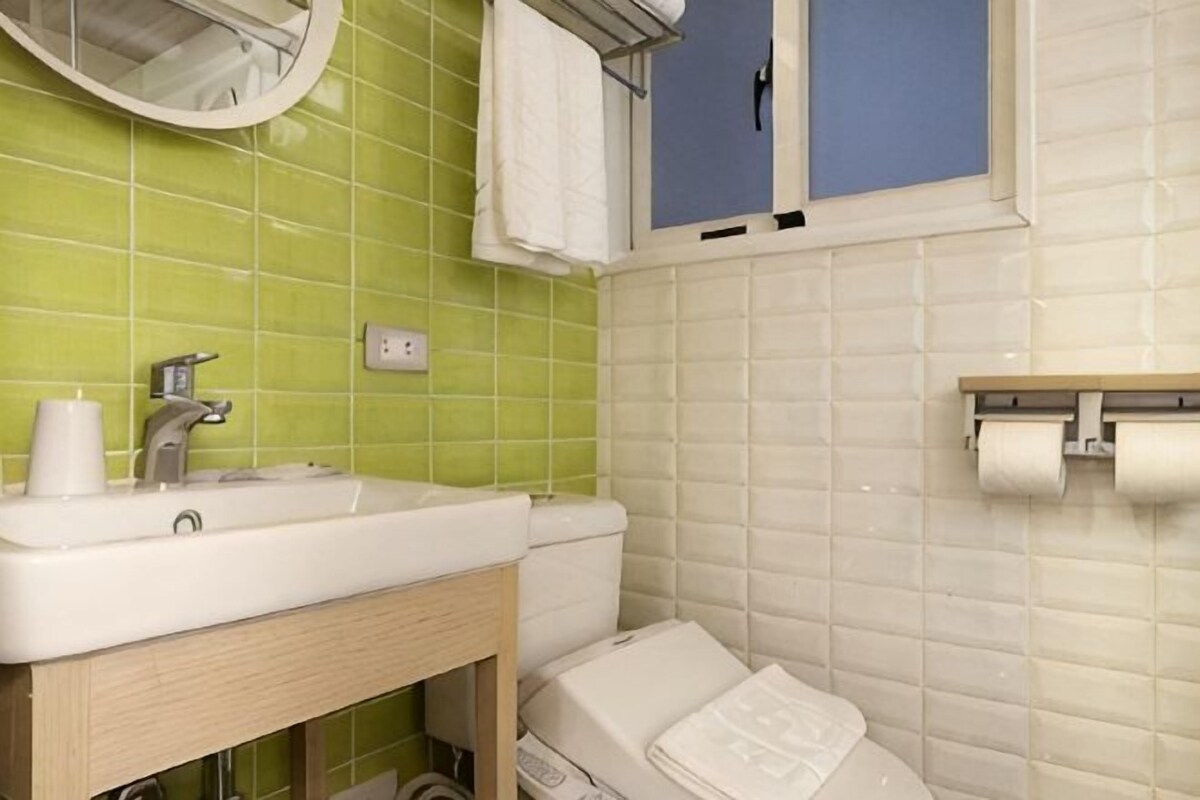 A bathroom with a sink, mirror, towel rack, and toilet paper holder.