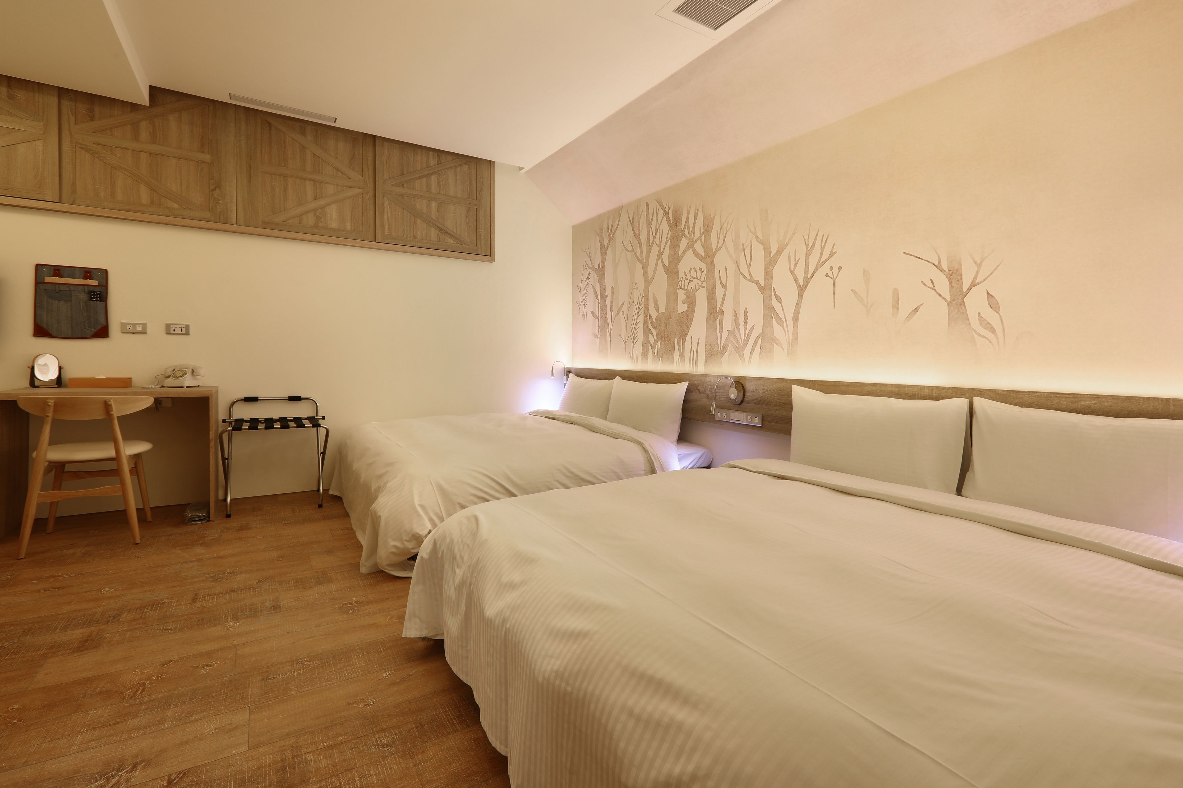 Quarto de hotel com duas camas, uma mesa e uma cadeira.