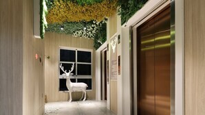 A modern hallway with a deer sculpture, an elevator, and a window with a night view. - Mini Hotels Taichung Station Branch (Taichung)
